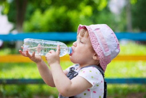 Little Girl Drinking from a plastic water bottle. 